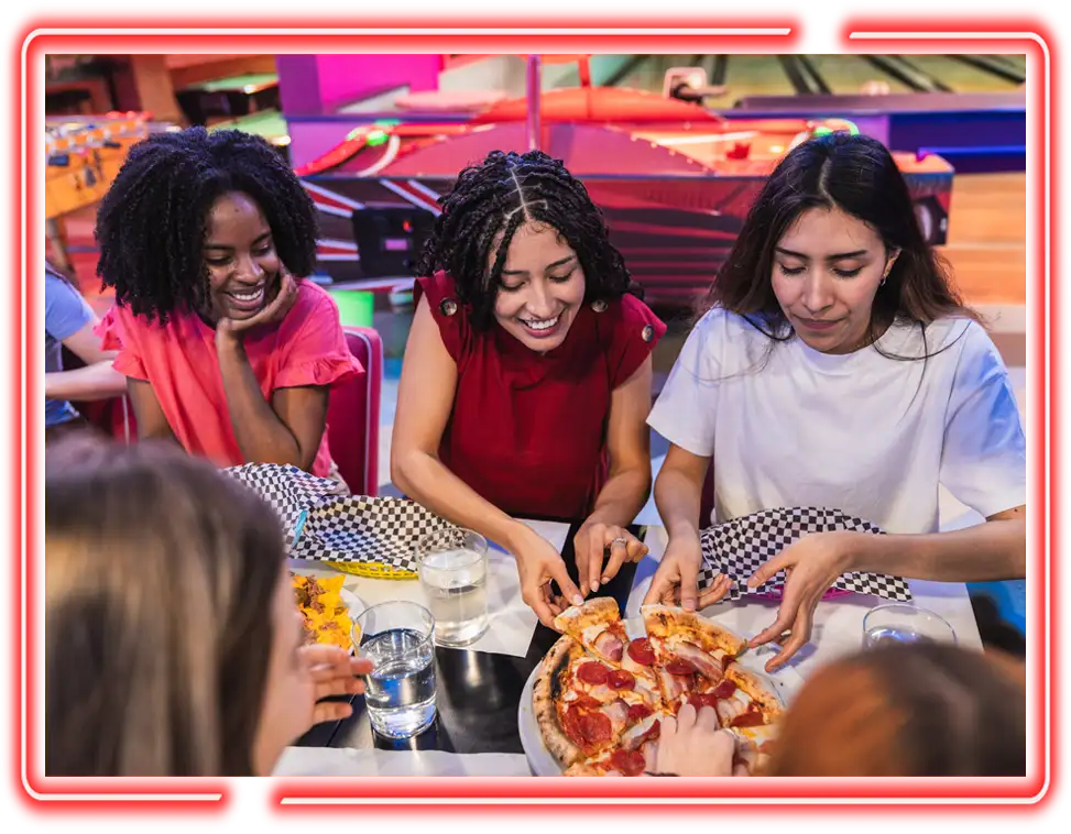 Friends sharing a pepperoni pizza at a bowling lane table at MAVRIX Sports pub in Jax 60 in Jackson, Michigan
