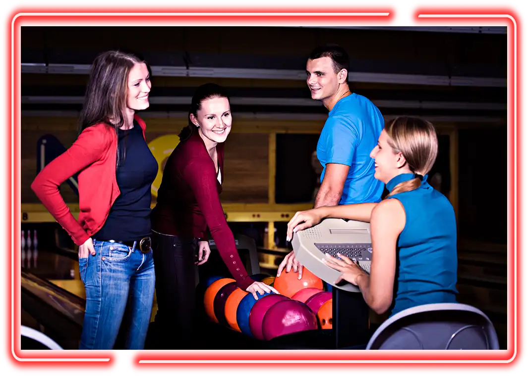 Coworkers selecting bowling balls from the rack while chatting at Jax 60 in Jackson, Michigan Team Building activity