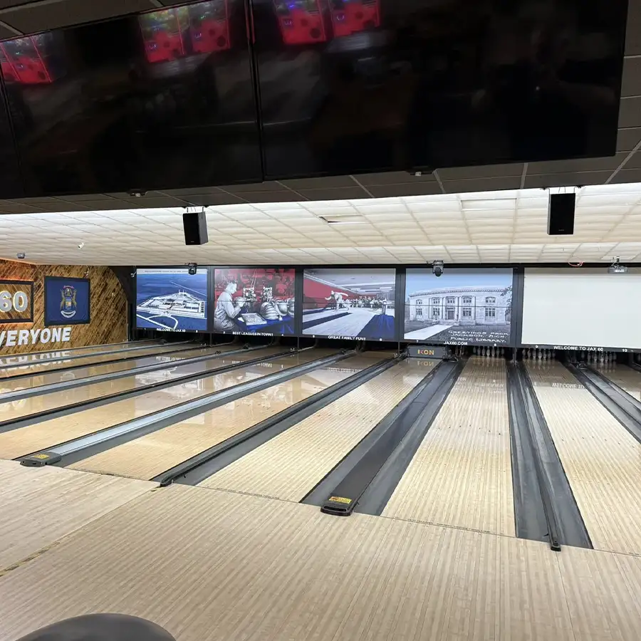 Bowling lanes with overhead screens displaying photos at Jax 60 in Jackson, Michigan