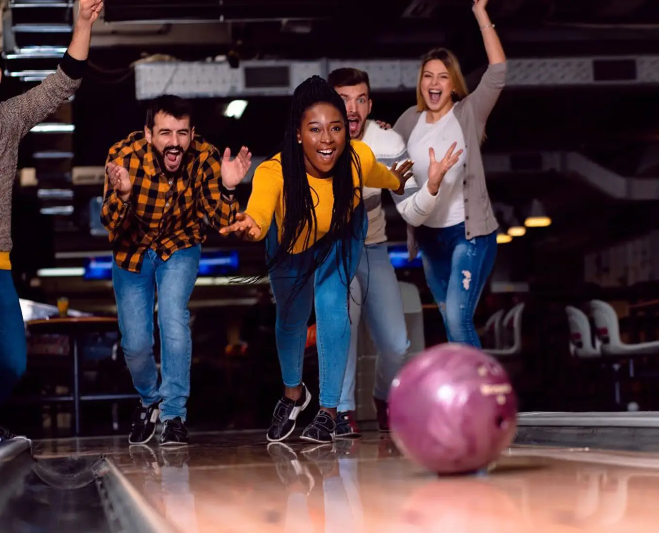 Group of friends cheering as a pink bowling ball rolls down the lane at Jax 60 in Jackson, Michigan